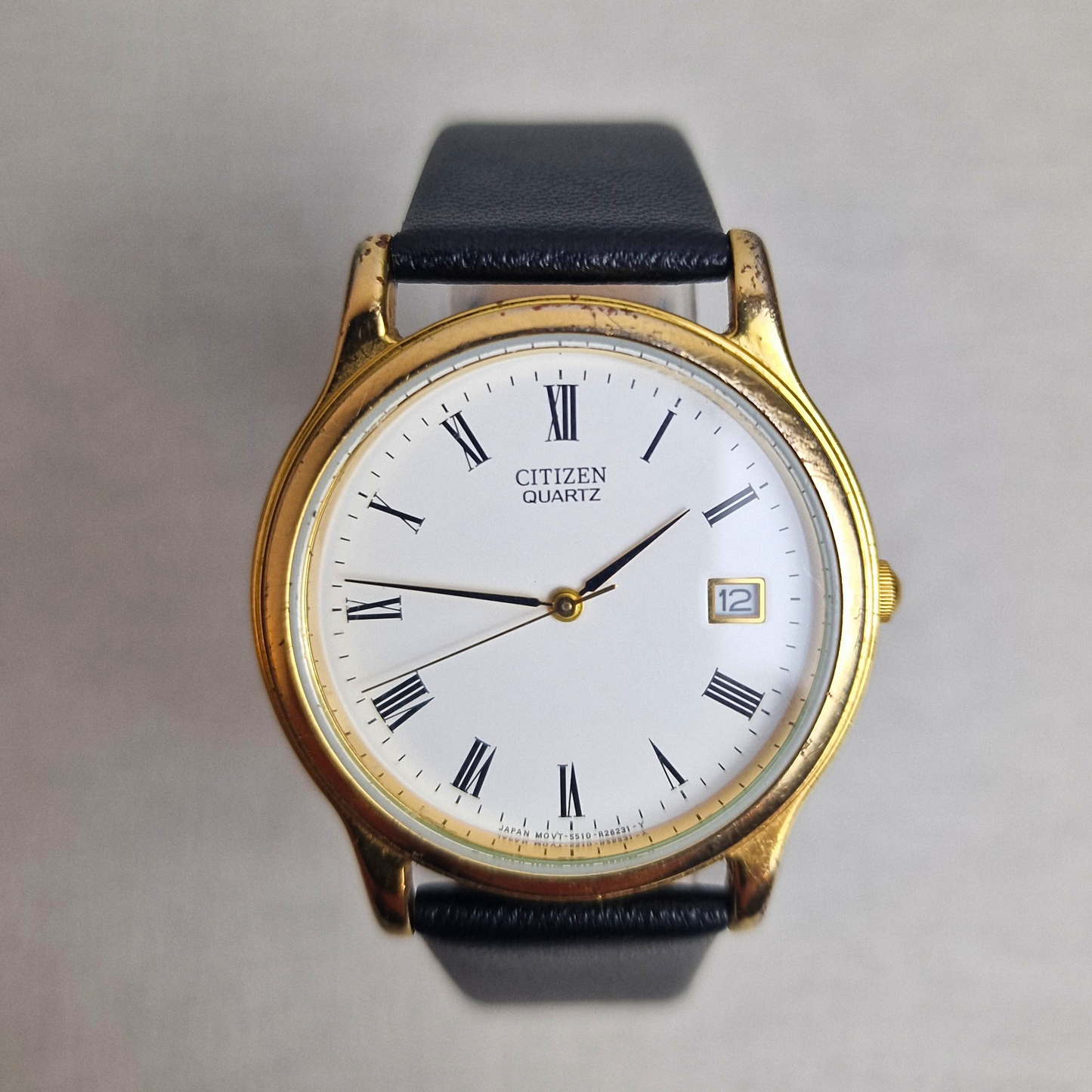 Vintage Citizen Watch Ref. 4121051 with gold-plated case, white dial, date display, and black leather strap. Classic 1980s quartz timepiece.